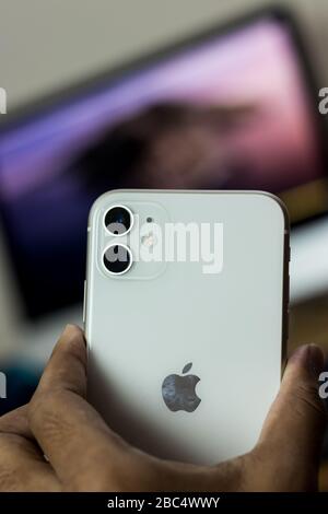 Sul retro dell'iPhone 11, variante bianca, tenendolo a portata di mano Foto Stock