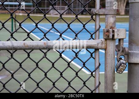 Primo piano del cancello con lucchetto di un campo da tennis con rete in background. Foto Stock