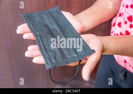 Maschera protettiva nera per il viso con mano di presa donna. Foto Stock