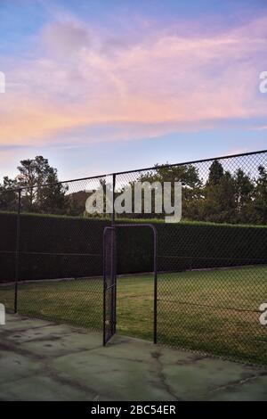 Porta aperta ad un vecchio campo da tennis in un giardino di una casa di campagna, nel tardo pomeriggio Mittagong, Southern Highlands, Australia Foto Stock