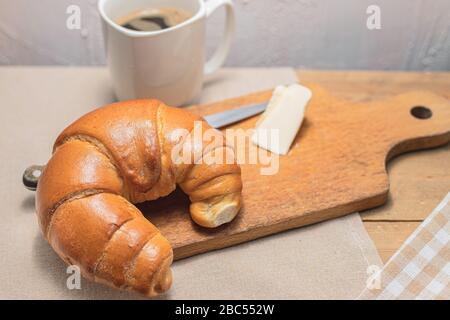 Croissant con caffè per colazione. Rotolo di burro in stile rustico. Pane al mattino. Pasto di campagna. Foto Stock