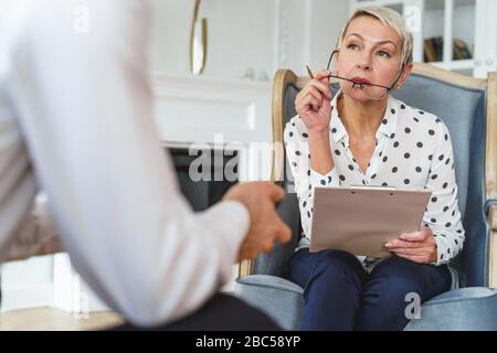 Psicologo professionale femminile che ascolta un cliente Foto Stock