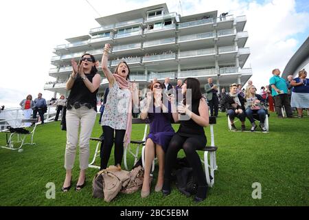 Racegoers acclamano sui loro cavalli mentre guardano le corse dal prato davanti allo stand della Regina a Epsom Downs Foto Stock