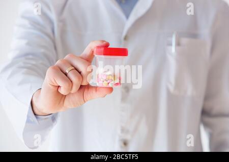 Chiudere le mani del medico con un vasetto di capsule Foto Stock