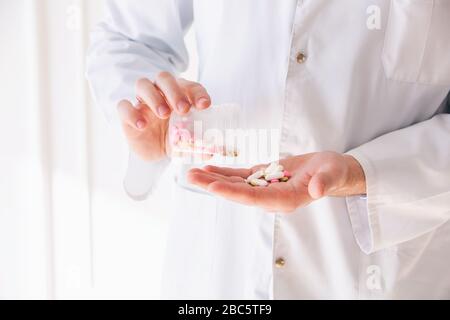 Primo piano mani del medico che tiene il pacchetto e le pillole Foto Stock