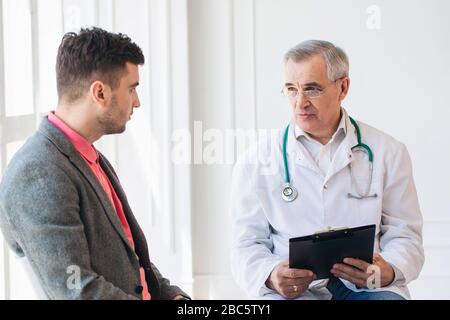 Senior consulta il medico paziente giovane Foto Stock