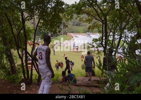 LILONGWE, MALAWI, AFRICA - 1 APRILE 2018: Un ragazzo che scende dalla zona degli alberi al campo d'erba della diga di Kamuzu II, dove gli adolescenti africani stanno avendo Foto Stock