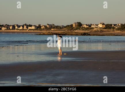 Saint Malo, Francia - 16 Settembre 2018: una donna a praticare yoga sulla spiaggia di Saint Malo nel bagliore del sole al tramonto. Brittany, Francia Foto Stock