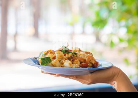 Mescolare il gambero fritto e il calamaro con il riso sul piatto in mano. Foto Stock