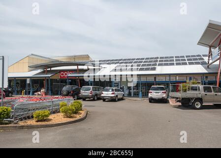 Auto parcheggiate fuori da un supermercato rurale Coles in un edificio con pannelli solari multipli sulla costa medio-settentrionale del nuovo Galles del Sud in Australia Foto Stock