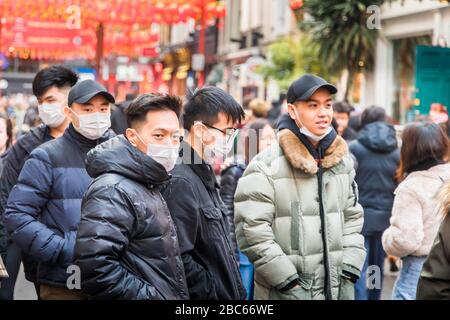 Giovani uomini asiatici/orientali che indossano maschere facciali, a 2020 celebrazioni cinesi del nuovo anno a Chinatown, Londra, a seguito di segnalazioni di epidemia di coronavirus Foto Stock