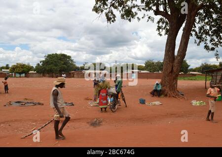 LILONGWE, MALAWI, AFRICA - 1 APRILE 2018: Strada luminosa scena, l'uomo africano è a piedi e donne africane con bambini stanno vendendo potatos, cabages e. Foto Stock