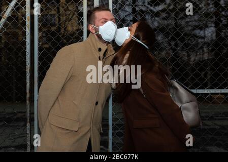 Giovane donna baciare un uomo sulla strada con maschera protettiva fuoco selettivo Foto Stock