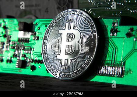 Moneta di bitcoin argento di fronte alla scheda madre del computer, il concetto di estrazione della criptovaluta e di investimento Foto Stock