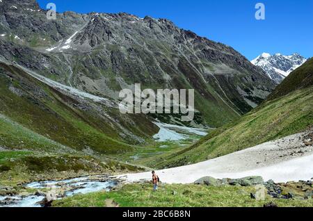 Austria, Tirolo, donna escursioni tra resti di neve e torrente nelle alpi austriache Foto Stock