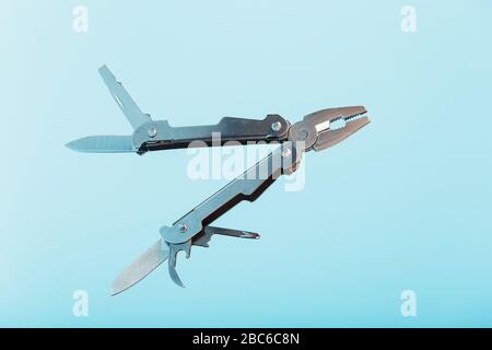 Lo strumento multifunzione multitool si trova su uno sfondo blu. Il concetto di un multi-utensile espanso con spazio libero. Foto Stock