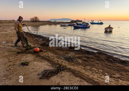 Un pescatore elimina vecchie corde e danni dalla spiaggia di Alexandroupoli Evros Grecia Foto Stock