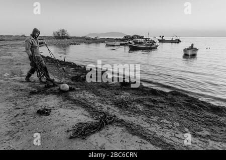 Un pescatore elimina vecchie corde e danni dalla spiaggia di Alexandroupoli Evros Grecia Foto Stock
