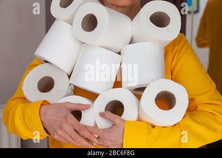 Una donna con un'armful di rotoli di toletta. Foto Stock