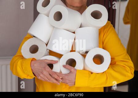 Una donna con un'armful di rotoli di toletta. Foto Stock