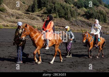 Due turisti femminili a cavallo attraversare il mare di sabbia lungo la strada per vedere il Monte bromo, bromo Tengger Semeru National Park, Giava, Indonesia. Foto Stock