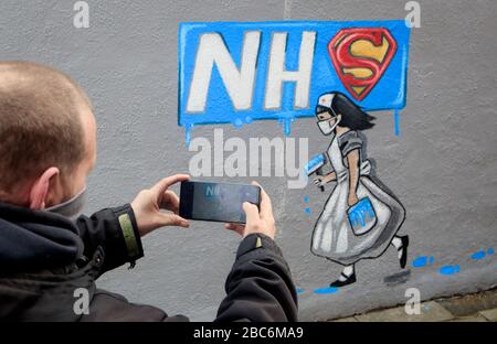 RITRASMISSIONE aggiungendo il nome dell'artista. Un uomo prende una fotografia di murale che sostiene il NHS, dall'artista Rachel List, sul lato del pub Horse Vaults a Pontefract, Yorkshire, come il Regno Unito continua in blocco per aiutare a frenare la diffusione del coronavirus. Foto Stock