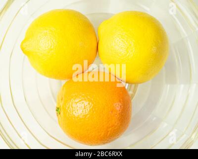 Un arancia e due limoni in una ciotola di frutta di vetro Foto Stock