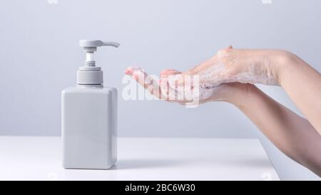 Mani lavate. Giovane donna asiatica che usa sapone liquido per lavare le mani, concetto di igiene per smettere di spargere coronavirus isolato su sfondo bianco grigio, Foto Stock