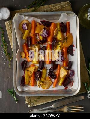 Verdure colorate arrostite su vassoio con pergamena. Mix di carote, barbabietole, rape, Foto Stock