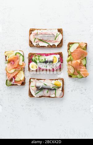 Saporito smorrebrod di pesce, set di cinque panini tradizionali danesi. Pane di segale nero Foto Stock