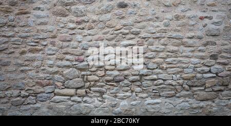 Vecchio muro grigio di pietra fatto di grandi piccole pietre naturali Foto Stock