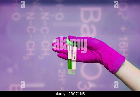 Una mano con guanti di gomma può contenere due provette con coronavirus Foto Stock