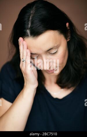 Donna ragazza con gli occhi chiusi toccando il tempio che avverte dolorosa sensazione di testa, di emicrania o mal di testa, o sensazione di stanchezza, stress, lavoro eccessivo. Foto Stock