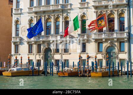Bandiere dell'Unione europea, dell'Italia e di Venezia sulla facciata di un vecchio edificio in una giornata di sole. Venezia, Italia Foto Stock