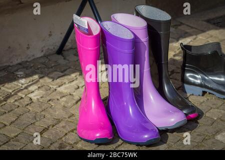 Cinque paia colorate di stivali in gomma rosa, viola, viola e nero Foto Stock