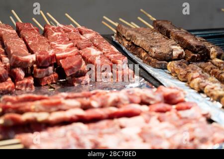 Spiedini di manzo alla griglia coreani crudi e cucinati su un vassoio. Cibi di strada coreani esposti a Myeongdong, Corea del Sud. Foto Stock