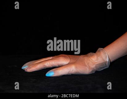 Mano di una donna con un manicure in un guanto di gomma trasparente. Foto Stock