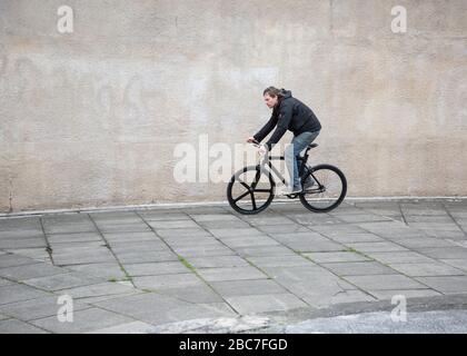 Uomo che guida una moto a velocità singola in un ambiente urbano Foto Stock