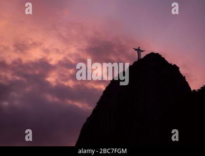 Silhouette di Cristo Redentore contro il cielo di crepuscolo viola Foto Stock