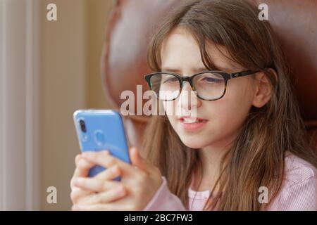 Sophie Rhian, 11, dedica del tempo al suo cellulare parlando con gli amici, isolando da sé la sua famiglia a Swansea Foto Stock