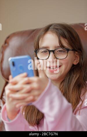 Sophie Rhian, 11, dedica del tempo al suo cellulare parlando con gli amici, isolando da sé la sua famiglia a Swansea Foto Stock