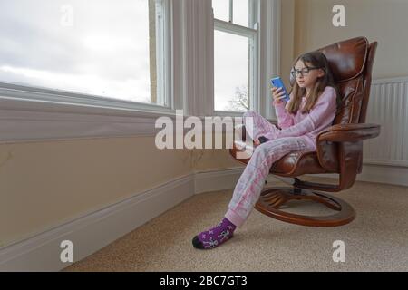 Sophie Rhian, 11, dedica del tempo al suo cellulare parlando con gli amici, isolando da sé la sua famiglia a Swansea Foto Stock