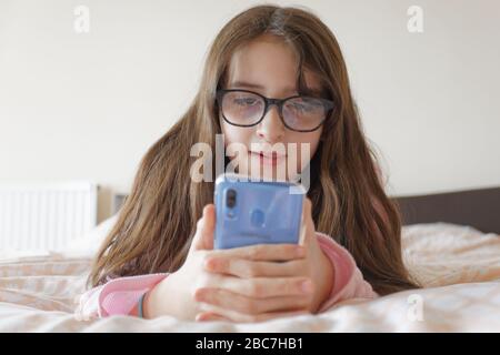 Sophie Rhian, 11, dedica del tempo al suo cellulare parlando con gli amici, isolando da sé la sua famiglia a Swansea Foto Stock