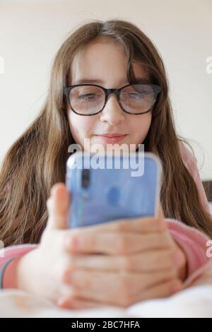 Sophie Rhian, 11, dedica del tempo al suo cellulare parlando con gli amici, isolando da sé la sua famiglia a Swansea Foto Stock