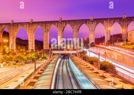 Vista sullo storico acquedotto della città di Lisbona (Aqueduto das Águas Livres), Portogallo. Stazione ferroviaria 'Campolide' in serata Foto Stock