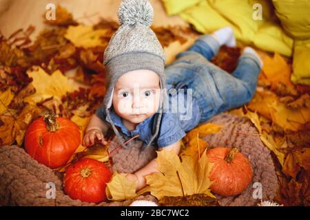 un ragazzino gioca in autunno lascia accanto alle zucche. foto dai colori caldi Foto Stock