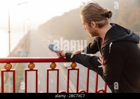 Attraente giovane sportivo in forma che lavora su un ponte, facendo esercizi di stretching Foto Stock