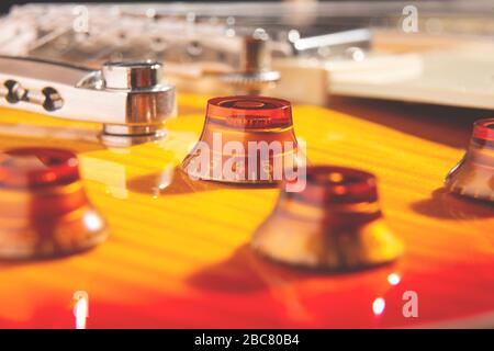 messa a fuoco selettiva sulla manopola ambra situata sulla parte superiore di una chitarra elettrica color ciliegia fiammata Foto Stock