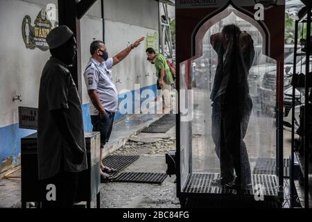 Medan, Sumatra settentrionale, Indonesia. 3rd Apr, 2020. i musulmani indonesiani attraversano una camera disinfettante prima di assistere alle preghiere del venerdì a Medan, nel Nord di Sumatra, il 3 aprile 2020, senza applicare regole di allontanamento sociale in mezzo alla preoccupazione per l'epidemia di coronavirus di Covid-19. L’Indonesia ha registrato 181 decessi correlati al COVID-19, il più alto numero di vittime del sud-est asiatico. I casi confermati nel paese sono inferiori di 1.986 "" rispetto alla Malaysia, alle Filippine e alla Thailandia, i dati riportati. Merito: Albert Ivan Damanik/ZUMA Wire/Alamy Live News Foto Stock