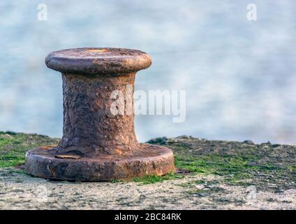 Un vecchio e arrugginito bollard per ormeggio sulla parete del porto di Staithes. Foto Stock